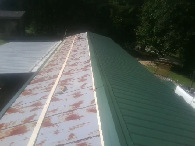 Old rusted panels beside newly installed green metal roofing — Wind Damage Roof Repair by Roofing Brothers in Boys Town
