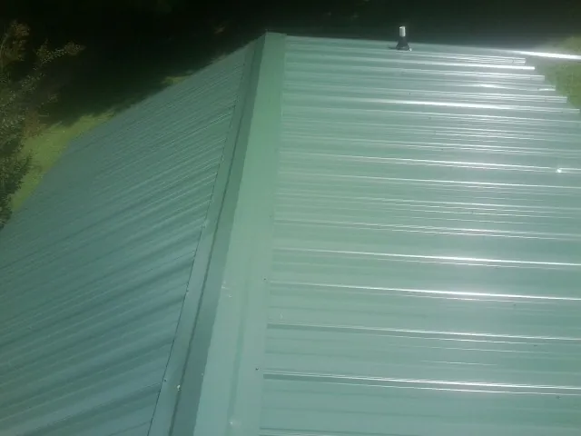 New green metal panels meeting at the ridge of a roof — Flat Roof Repair work by our crew in Boys Town