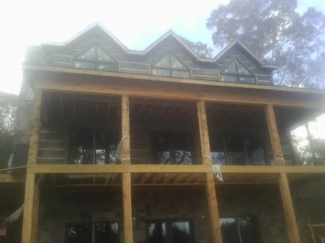 Dormers and porch framing on a large log home under construction — Roof Coating work by our crew in Boys Town