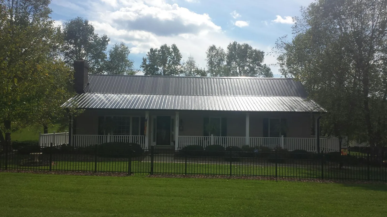 Gray metal roof on a brick ranch with a full width front porch — Gutter Guard Installation work by our crew in Boys Town