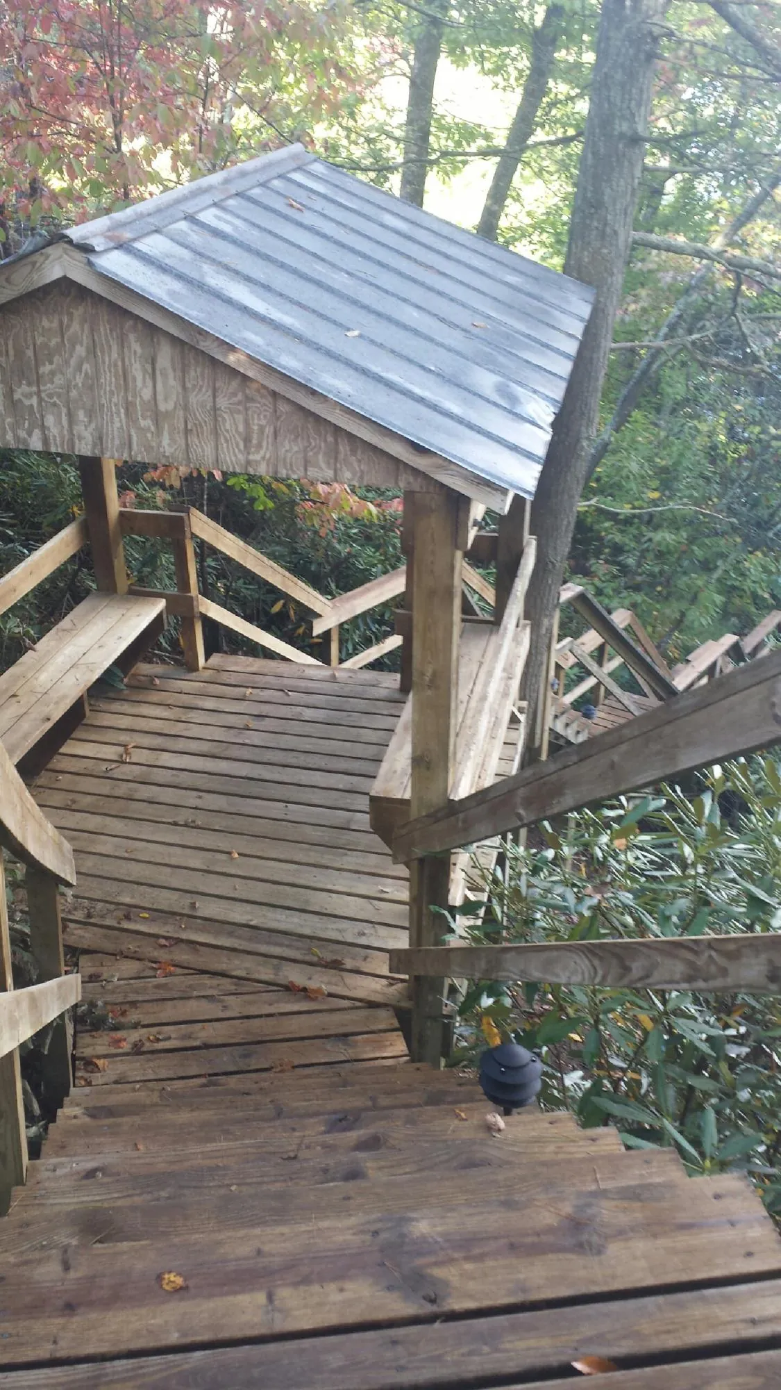 Metal roofed shelter over wooden steps on a wooded walkway — Skylight Repair & Installation work by our crew in Boys Town