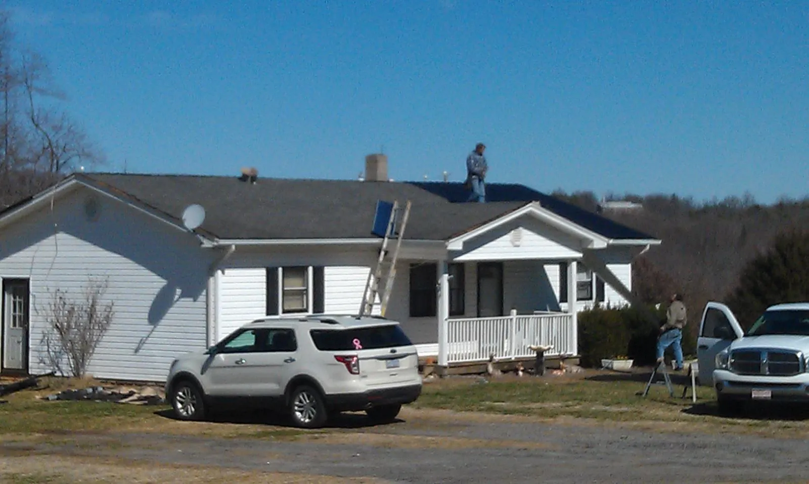 Roofers stripping shingles from a white ranch house roof in Boys Town