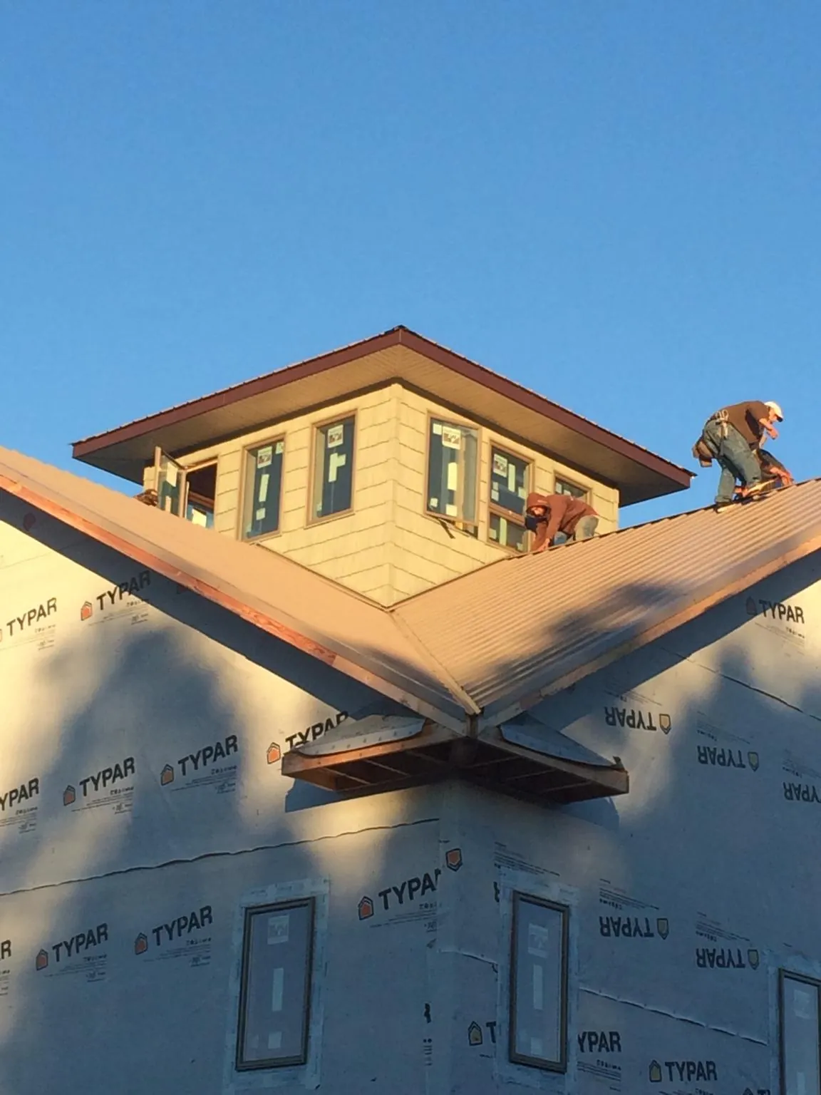 Roofers working around a rooftop cupola on a new metal roof at sunset — Roof Waterproofing in Boys Town by Roofing Brothers